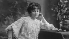 Portrait of Marie Bonaparte sitting at a table, with a vase of flowers.
