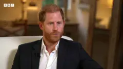 Prince Harry wearing a black jacket and white shirt
