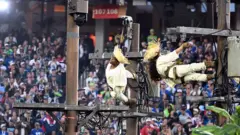 dos bailarines cuelgan de postes eléctricos que simulan la infraestructura de la isla en el show de medio tiempo de bad bunny en el superbowl.