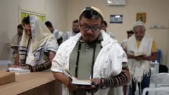 Homens com trajes ritualísticos judaicos durante oração em sinagoga