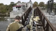 Des soldats traversant un pont endommagé.