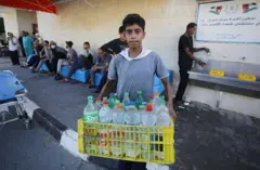 طفل في غزة يحمل قوارير مياه