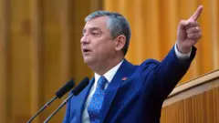 CHP Genel Başkanı Özgür Özel'in 21 Nisan 2026'daki grup konuşması. Üzerinde mavi bir takım elbise var parmağını uzatıp konuşuyor. 