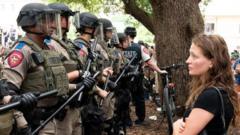Un étudiant regarde une file de soldats de l’État du Texas lors de manifestations.