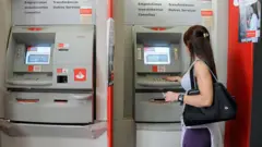 Mulher saca dinheiro no caixa eletrônico