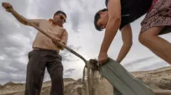 بعض السكان يجهزون عبوات الرمال لصد المياه.