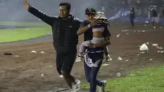 শিশু কোলে নিয়ে দৌড়াচ্ছে এক দর্শক।