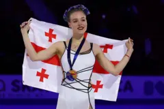 бывшая гражданка России фигуристка Анастасия Губанова стоит на подиуме с грузинским флагом