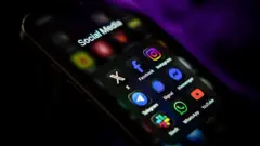 Telefone celular mostrando ícones de redes sociais e aplicativos de mensagens na tela