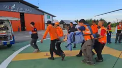 Seroang pria sedang ditandu beramai-ramai untuk diselamatkan.