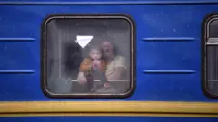 A woman and a child look through the window of a train as they flee the country, at the Lviv train station, western Ukraine, on March 5, 2022