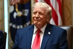 الرئيس الأمريكي دونالد ترامب يرتدي سترة زرقاء وقميصاً أبيض وربطة عنق حمراء.
