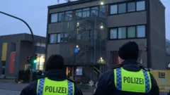 Dois policiais de costas observando prédio