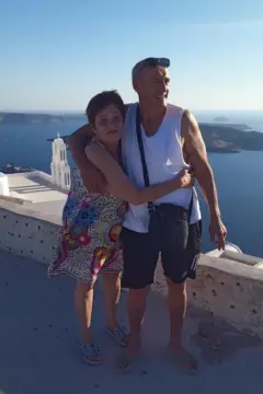 Andrea e Alejo posam com o que parece ser o mar e pequenas ilhas ao fundo. Ela está de vestido e o abraça pela cintura, enquanto ele, vestindo uma camiseta sem mangas, envolve o braço em volta das costas dela.
