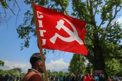 Un trabajador subcontratado sostiene la bandera del Partido Comunista de la India (Marxista) (CPI-M) durante una manifestación