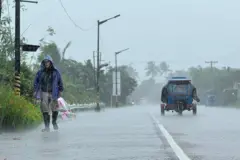 A man walks along a road amid heavy rain due to weather patterns from Super Typhoon Ragasa in Lal-lo town, Cagayan province on September 22, 2025