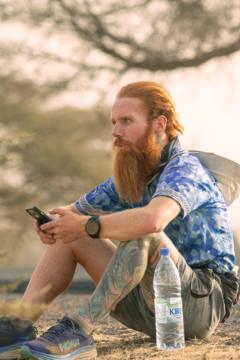 Cook esperando sentado con el celular en la mano.