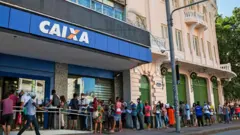 Fila de pessoas em frente à Caixa Econômica Federal esperando para receber o auxílio emergencial