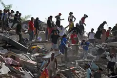 Enquanto um grupo de pessoas procura sobreviventes, outras tentam recuperar seus pertences em um edifício que desabou.