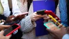 Mãos de adolescentes com seus celulares