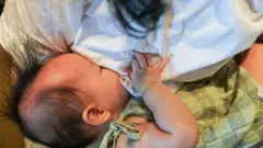 Mulher amamentando um bebê na China