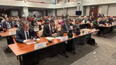 Empresários sentados em uma sala fechada durante reunião.