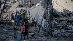 Palestinos ao lado de um prédio demolido na Cidade de Gaza