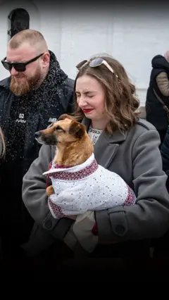 Жінка тримає на руках собаку