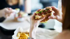 Femme mangeant un hamburger végétarien.