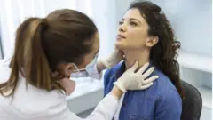 Médica examinando pescoço de paciente
