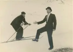 Dois homens na neve. Dennis está em cima de um instrumento para esquiar