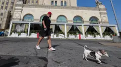Muškarac sa psom gleda u zgradu oštećenu od eksplozije