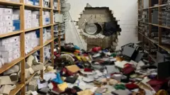 یک حفره در دیوار چند لایه اتاقی ایجاد شده، اتاق دارای قفسه‌هایی است و اشیایی روی زمین پخش و پلا شده است