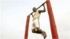 Un homme fait des tractions le long de la plage le 7 juin 2004 à Dakar, Sénégal.
