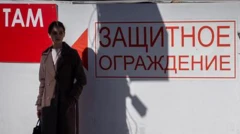 Женщина стоит у надписи на стене "Защитное ограждение" в Белгороде