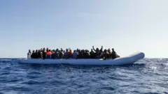 লিবিয়ার উপকূলের অদূরে সাগরে ভেসে বেড়ানো অভিবাসনকামীদের নৌকা।