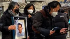 Relatives carry a picture frame of a loved at a crematorium in Beijing on December 20, 2022.