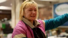 Woman in pink jacket crying