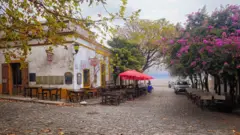 O centro histórico de Colonia del Sacramento, no Uruguai, com ruas de paralelepípedos, mesas nas calçadas e primaveras em flor