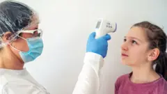 Profissional de saúde mede a temperatura de criança