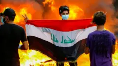 Bağdat'taki protestolarda bir genç Irak bayrağıyla poz veriyor