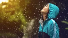 ዝናብ እየመታት ደስተኛ የሆነች ሴት 