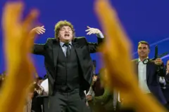 Milei em palco, com Flávio Bolsonaro ao fundo