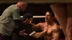 Cena do filme em que Johnson está na lateral do ringue, sentado, conversando com o treinador