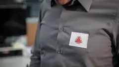 Detalhe da camisa de Zema, com uma bandeira de Minas Gerais no peito. A bandeira é branca com um triângulo vermelho no centro e a frase em latim "Libertas quae sera tamen" (Liberdade, ainda que tardia)