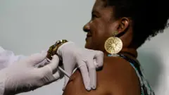 Mulher é vacinada no braço. 