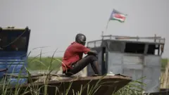 رجل من جنوب السودان يجلس على متن قارب على نهر النيل في ميناء رينك النهري، في بلدة رينك بولاية أعالي النيل في جنوب السودان في 14 مايو/أيار 2023 