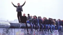 Jerman Barat merayakan keruntuhan komunisme di atas Tembok Berlin, tanggal 12 November 1989.