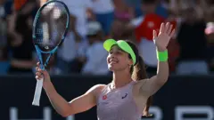 Zeynep Sönmez elindeki raketini kaldırmış halde diğer eliyle de selamlıyor