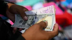 Un hombre sujeta unos billetes de dólares y bolívares.